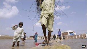 Pakistanis cross a flooded way in Badin district, in Pakistan's Sindh province, Sunday, Sept. 25, 2011.