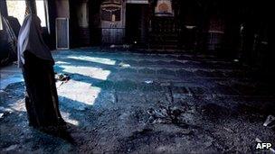 A woman standing in a burned-out mosque in Tuba-Zangariya, Israel, 3 October 2011