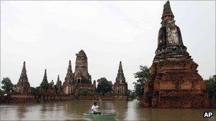 A man rows his boat past Chaiwatthanaram temple which was hit by floods in Ayutthaya province, central Thailand, 4 Oct