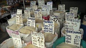 A Thai vendor carries a variety of rice to refill a bag at his shop at a market in Bangkok