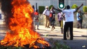 A protester burns vegetation in a street in Lilongwe, Malawi, as anti-government demonstrations swept across the country amid worsening economic conditions - 20 July 2011