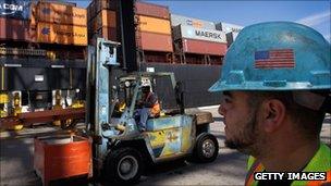 Longshoremen work next to a container ship at Port Everglades