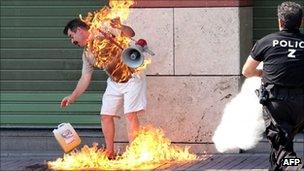 Policeman rushes to extinguish a man who set himself on fire outside a bank in Thessaloniki (September 16, 2011)