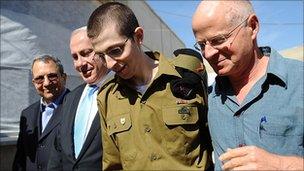 freed Israeli soldier Gilad Shalit (2nd R) walks with (L-R) Defence Minister Ehud Barak, Israeli Prime Minister Benjamin Netanyahu his father Naom Shalit at Tel Nof Airbase on October 18, 2011 in central Israel.