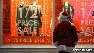 Someone dressed as Father Christmas looking at a pre-Christmas window display