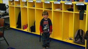 Child stands in front of classroom cubbies