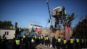 Police gather around the base of a makeshift tower.