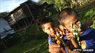 Boys hold toy robots outside their house in Sarawak