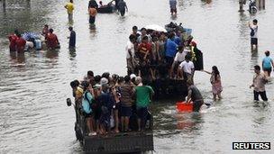 People are evacuated on trucks from a flooded area in Bangkok"s suburbs October 20, 2011