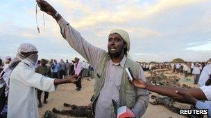 An al-Shabab spokesman addresses the media next to what they say are the bodies of 76 Burundian peacekeepers from the African Union Mission to Somalia killed during heavy fighting in Dayniile district, south of Mogadishu October 20, 2011.