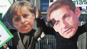 Protesters dressed as German Chancellor Angela Merkel and French President Nicolas Sarkozy