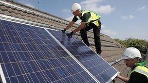 Workmen installing solar panels on to the roofs of homes in Delabole near Bodmin