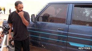 A man looks at shots in a window of a car which was used to try to stop kidnappers in Tindouf on 23 October 2011.