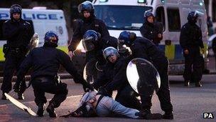 Police detain a man during rioting in Birmingham