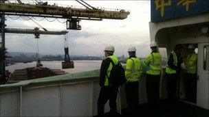 Men watching iron ore being moved