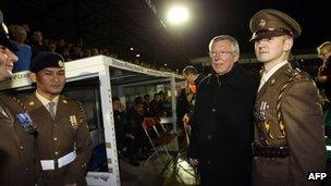 Sir Alex Ferguson poses with soldiers beside the dugout ahead of the match at Aldershot