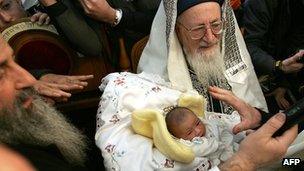 Israel's Rabbi Mordechai Eliyahu carries an eight-day-old baby during a circumcision ceremony in front of the Knesset (Israeli Parliament) in Jerusalem 10 January 2004.