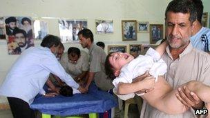 A man holds his son after circumcision at a clinic in Sadr city, Iraq