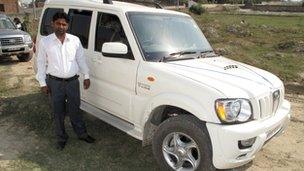 A farmer poses with a new car he's bought with the compensation money