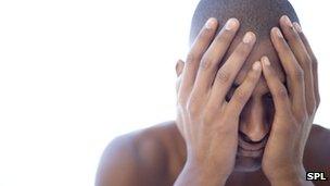 Depressed young man holding his face in his hands