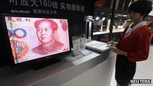 An employee operates a camera to zoom in on the image of a Chinese 100 yuan banknote at a production exhibition in Wuhan, Hubei province, on 13 October 2011