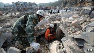 Firefighters search through debris after an explosion at an auto repair workshop on a highway in Fuquan, in southwest China's Guizhou province on November 1