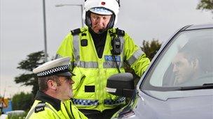 Traffic police officers speak to a driver