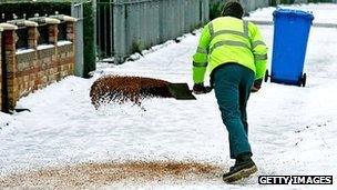 Worker spreads grit in residential area - generic image