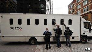 Photographers take pictures through the window of a prison van as it leaves Southwark Crown Court in London, on November 3, 2011