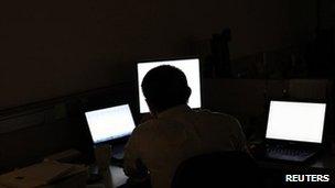 A man in front of several computer monitors