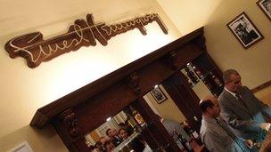 Bartenders fix drinks under an Ernest Hemingway sign