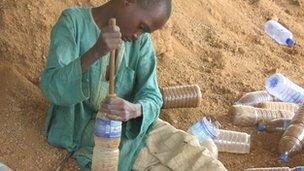 A child in Yelwa packing bottles with sand