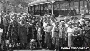 Happy holidaymakers pose near their bus