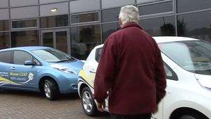 Man next to two Nissan leaf electric cars