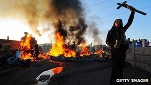 A traveller holds aloft a crucifix as a caravan burns on Dale Farm, near Basildon, east of London, on October 19, 2011