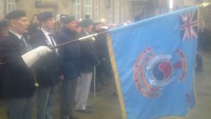 A flag is lowered during a service in Queen's Square in the centre of Wrexham