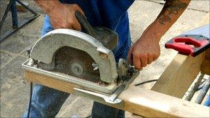 Worker cutting wood with electric saw