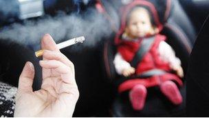 Smoking cigarette in a car with a small child in the back seat.