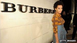 A model wearing Burberry clothes in front of their sign