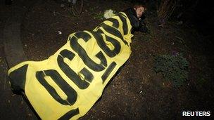 A protester lies down under an Occupy banner in Zuccotti Park 15 November 2011