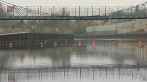 Bright orange buoys stop river traffic from sailing underneath the Victoria Bridge on the River Avon in Bath