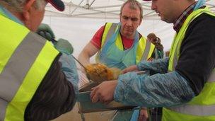 volunteers ladle curry from a large vatt