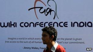 A participant walks past a poster advertising Wikipedia's Mumbai meeting