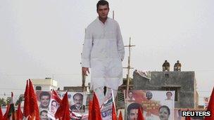 Indian policemen guard from the roof of a house next to a giant cut-out of Rahul Gandhi in Uttar Pradesh