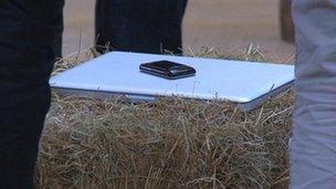 A Macbook and Blackberry on a bale of hay bale