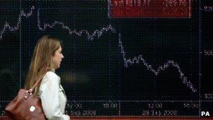 Woman walks past share index screen