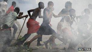Opposition UDPS supporters run through a cloud of tear gas outside N'Djili airport in Kinshasa