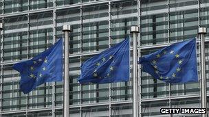 European Union flags blow in a breeze outside one of the buildings of the European Commission