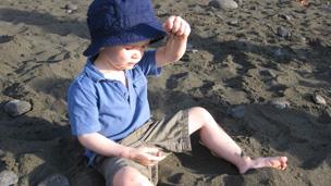 Child plays on dark sand beach