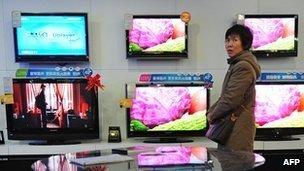 A woman walking past television sets on display at an electronics and home appliances store in Zhengzhou in central China's Henan Province (file photo)